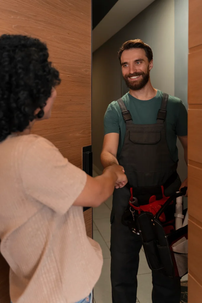 Profesional de mantenimiento dando la mano a una clienta en la puerta de su hogar, simbolizando la confianza, atención personalizada y servicio técnico de Vive Protegido.