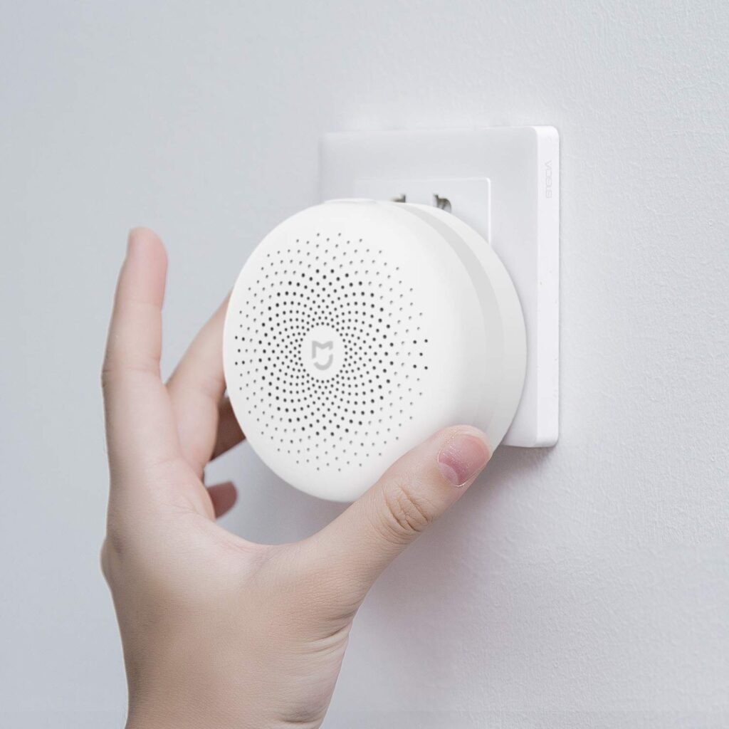 Mano instalando el hub central Xiaomi Mi Control Hub en un enchufe de pared para alarma sin cuotas