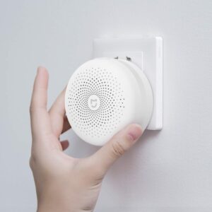 Mano instalando el hub central Xiaomi Mi Control Hub en un enchufe de pared para alarma sin cuotas